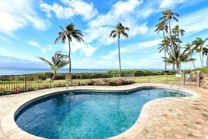A swimming pool with a curved design, surrounded by a stone deck and a metal fence. - New 70 Feet from Ma'alaea Bay, Pool and Hot Tub (Wailuku)