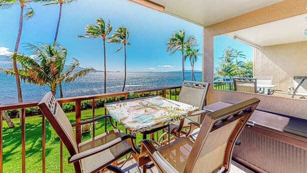 A balcony with a table and chairs, overlooking a view of palm trees and the ocean. - New 70 Feet from Ma'alaea Bay, Pool and Hot Tub (Wailuku)