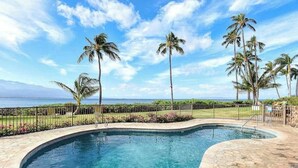 A swimming pool with a curved edge, surrounded by a stone deck and a metal fence. - New 70 Feet from Ma'alaea Bay, Pool and Hot Tub (Wailuku)