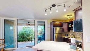 Une cuisine moderne dotée d’un grand îlot central, de portes-fenêtres coulissantes donnant sur un patio et d’un luminaire suspendu au plafond.