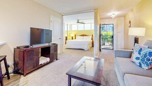 Une chambre d’hôtel équipée d’une télévision, d’un canapé, d’une table basse en verre, d’un lit et d’un balcon avec vue.