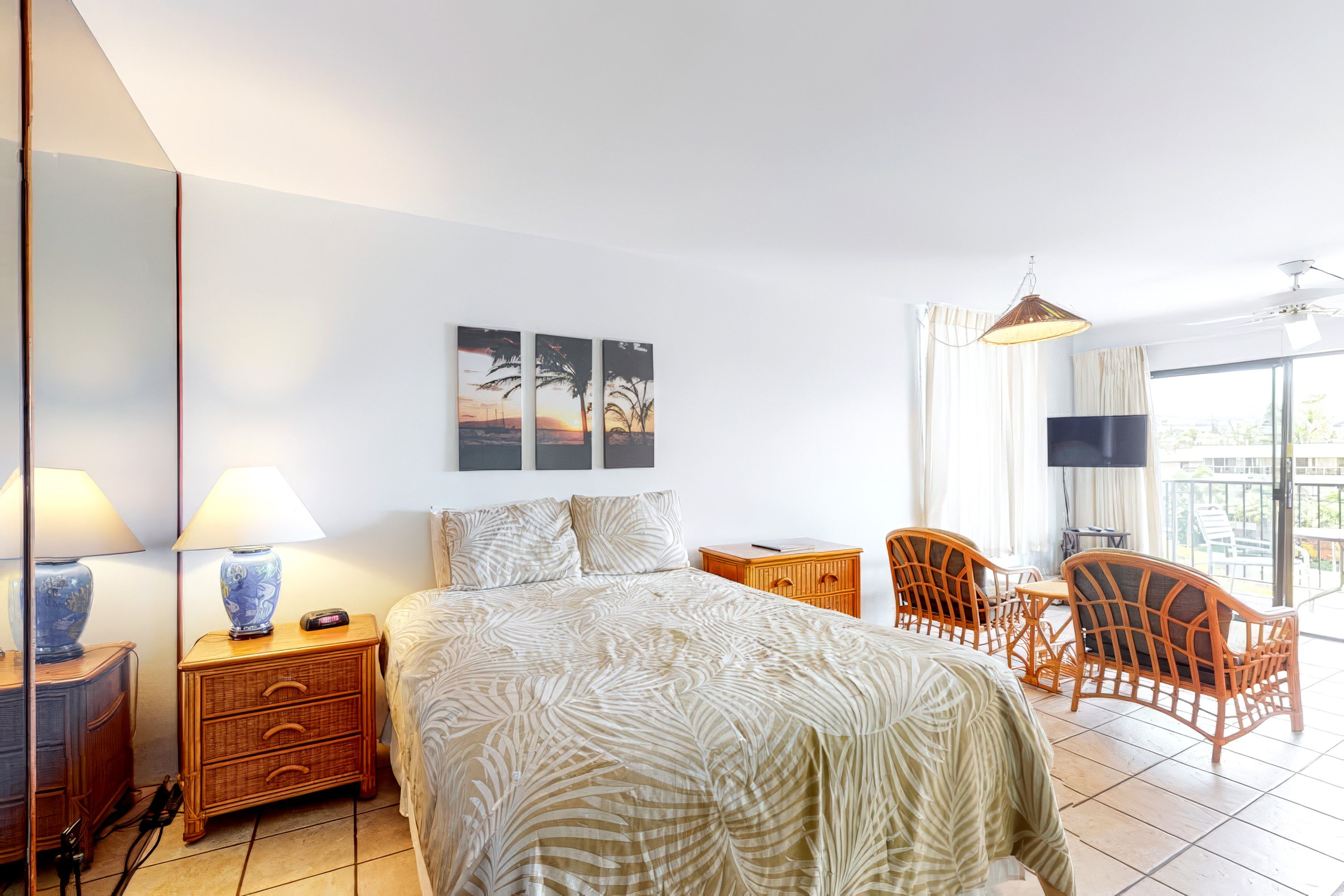 A hotel room with a bed, a desk with a chair, a TV, and artwork on the wall.