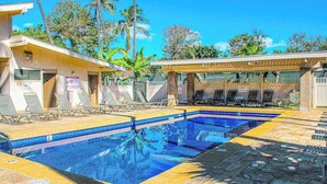 Ein Pool mit Liegestühlen, eine überdachte Sitzecke und ein Gebäude mit einem Verbotsschild.