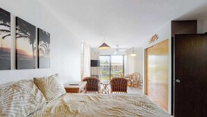 Ein Schlafzimmer mit Bett, einem Balkon mit Stühlen und Blick ins Freie.