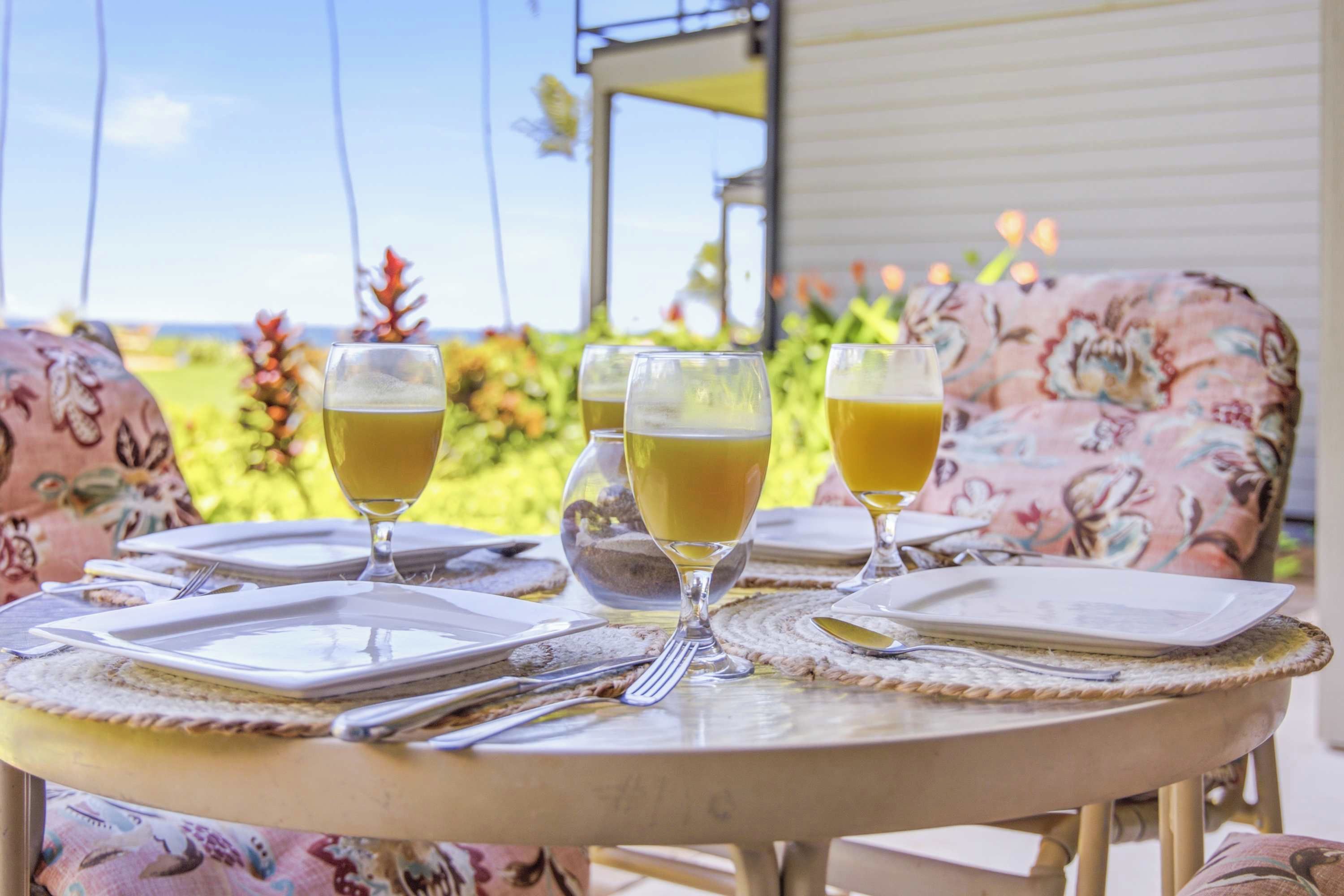 Ein Tisch draußen gedeckt mit Tellern, Gläsern und Besteck, mit Blick auf einen Garten.