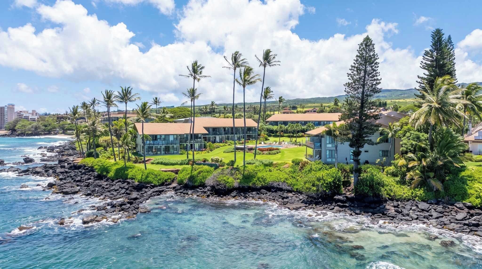 A coastal property with multiple buildings, a rocky shoreline, and clear blue waters.
