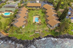 Ein Resort mit einem zentralen Pool, mehreren Gästezimmern und Blick auf den Ozean.