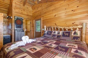 A wooden cabin room with a bed, a dartboard, and a door with a window. - Sunrise Pointe (Sevierville)