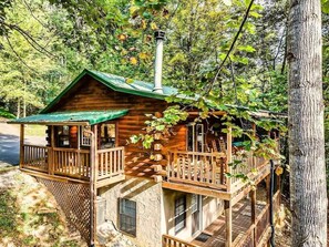 A wooden cabin with a green roof, a balcony, and a chimney. - The Blessing Cabin (Sevierville)