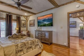 Ein Schlafzimmer mit Bett, Deckenventilator, Kommode und einem Bild an der Wand.