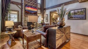 A spacious living room with a fireplace, leather furniture, and large windows. - The Cub House (Sevierville)