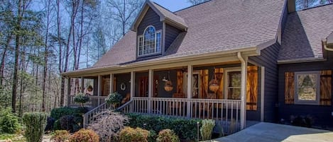 A two-story house with a covered porch, a front staircase, and a well-maintained garden.