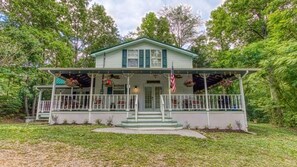 A two-story house with a porch, a small front yard, and a flag. - The Farmhouse (Sevierville)