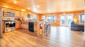 A wooden cabin interior with a kitchen, dining area, and living room. - Time To Unwind (Sevierville)