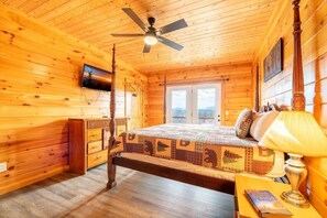 A wooden cabin room with a bed, a ceiling fan, a dresser, and a window. - Time To Unwind (Sevierville)