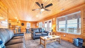 A log cabin interior with a ceiling fan, a sofa, a coffee table, and a dining area. - Time To Unwind (Sevierville)