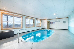 A swimming pool with a metal ladder, large windows, and a view of the outdoors. - Time To Unwind (Sevierville)
