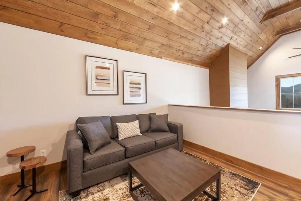 Un soggiorno moderno con un divano grigio, un tavolino e travi a vista in legno.
