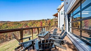 Terraza con mobiliario exterior y una parrilla, con vistas a un paisaje montañoso.