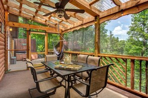 A covered outdoor area with a table and chairs, a hammock, and a view of the forest. - Z - Treehouse Overlook (Sevierville)