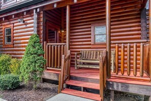 A log cabin with a porch, steps, a bench, and a small tree. - Z - Uncle Buck's Cabin (Pigeon Forge)