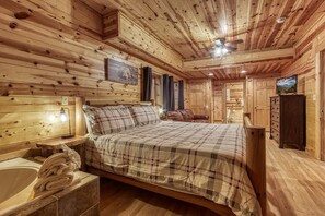 A wooden cabin bedroom with a bed, a nightstand, a dresser, and a television. - Z - Uncle Buck's Cabin (Pigeon Forge)