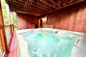 A hot tub with a wooden deck and brick walls. - Z - Uncle Buck's Cabin (Pigeon Forge)
