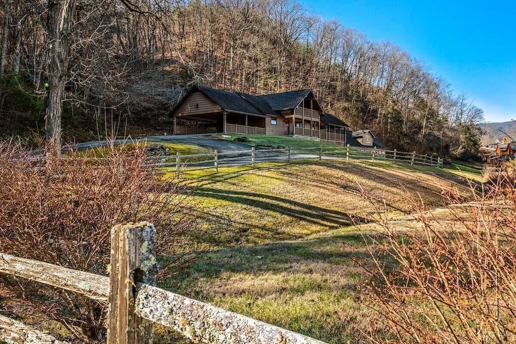 A rustic cabin with a sloped roof, surrounded by a fenced property with a clear path leading to the entrance.