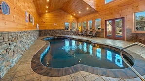 Un intérieur en bois avec une piscine, des murs en pierre et une vue sur l’extérieur.