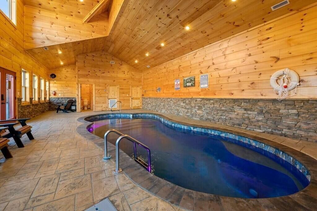 Une piscine intérieure avec des murs en bois et des éléments décoratifs en pierre, des bancs et une bouée de sauvetage fixée au mur.