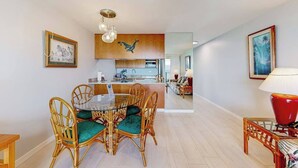 Un comedor con una mesa redonda y sillas, una cocina al fondo y una sala de estar con sofá y lámpara.