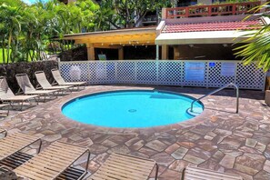 Ein Swimmingpool mit Liegestühlen, einer Fliesen-Terrasse und einem überdachten Bereich mit rotem Dach.