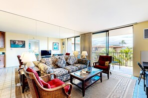 A hotel room with a sofa, armchairs, a coffee table, a TV, and a balcony with a view. - NEW Fall Sale Ocean-View Kihei Penthouse for Sunset Stays (Kihei)