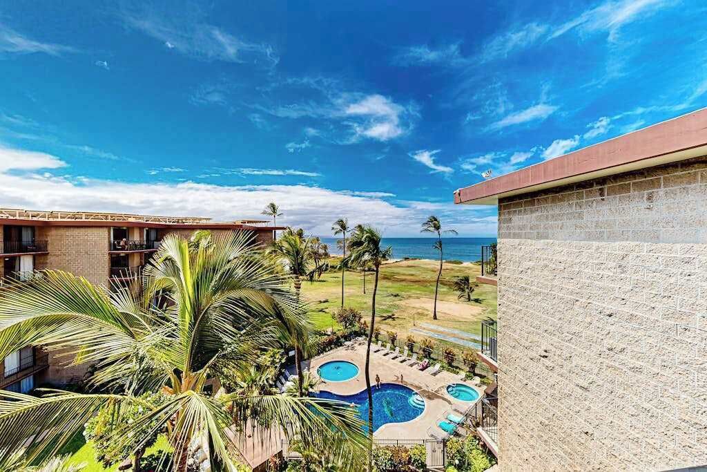 Un hôtel doté d’une piscine, de palmiers et offrant une vue sur l’océan.