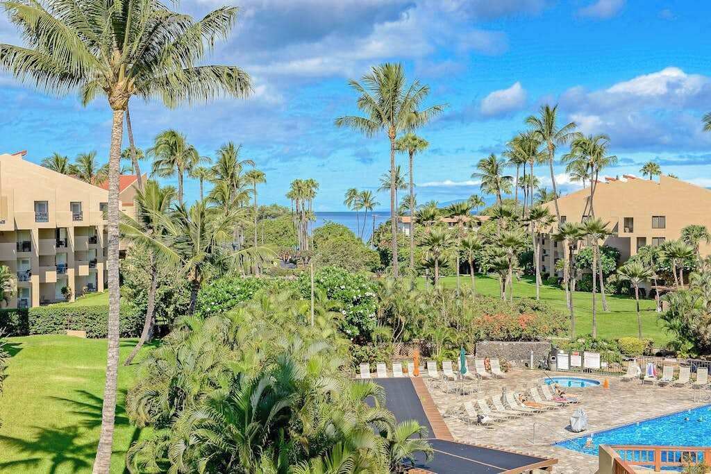 A resort with multiple buildings, a swimming pool, and palm trees.