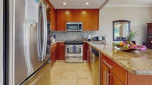 Una cocina con armarios de madera, electrodomésticos de acero inoxidable, encimeras de granito y un horno empotrado.