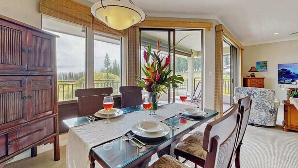Un comedor con mesa de vidrio, sillas, un armario de madera y un ventanal con vistas.