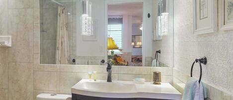 A bathroom with a large mirror, a sink, a toilet, and a towel rack.