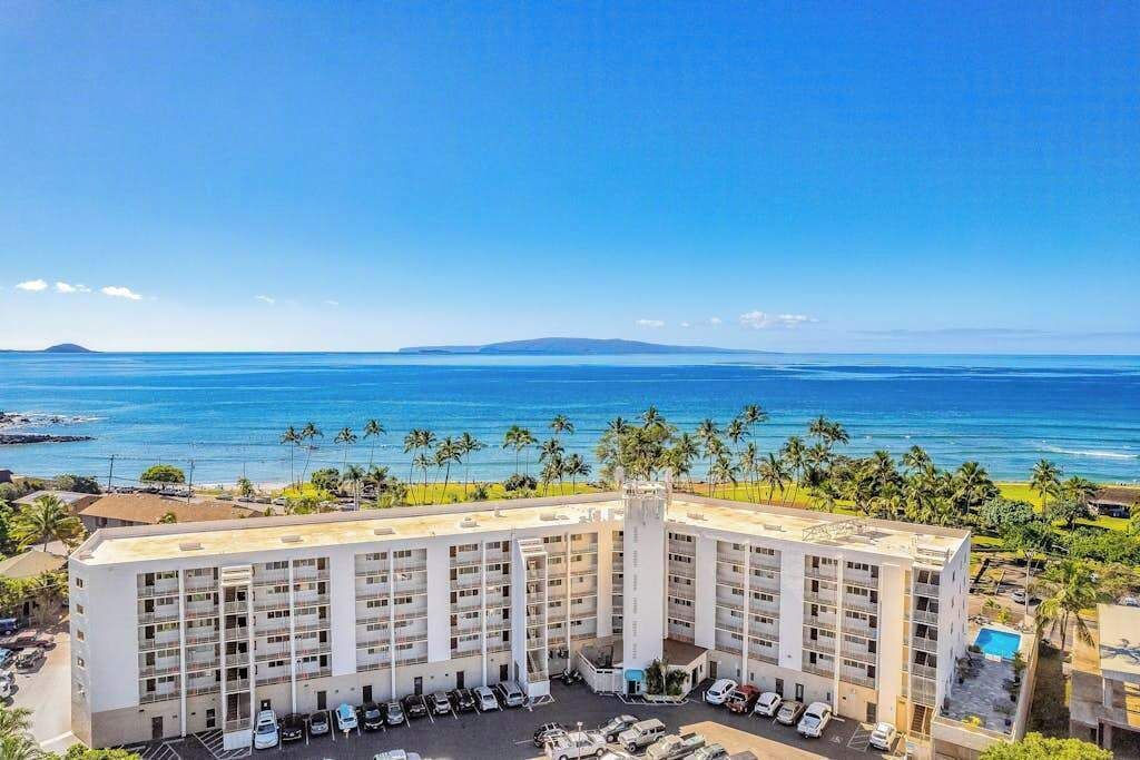 Un hotel a più piani con un cortile centrale, un'area parcheggio e vista sull'oceano.