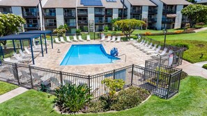 Une piscine entourée d’une terrasse, de chaises longues et d’un espace salon abrité.