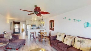 Ein Wohnzimmer mit Sofa, Hocker, Couchtisch und Deckenventilator.