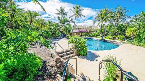 Un resort con piscina rodeada de exuberante vegetación y palmeras.