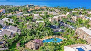 Un resort con varias edificaciones, una piscina y vista al océano.
