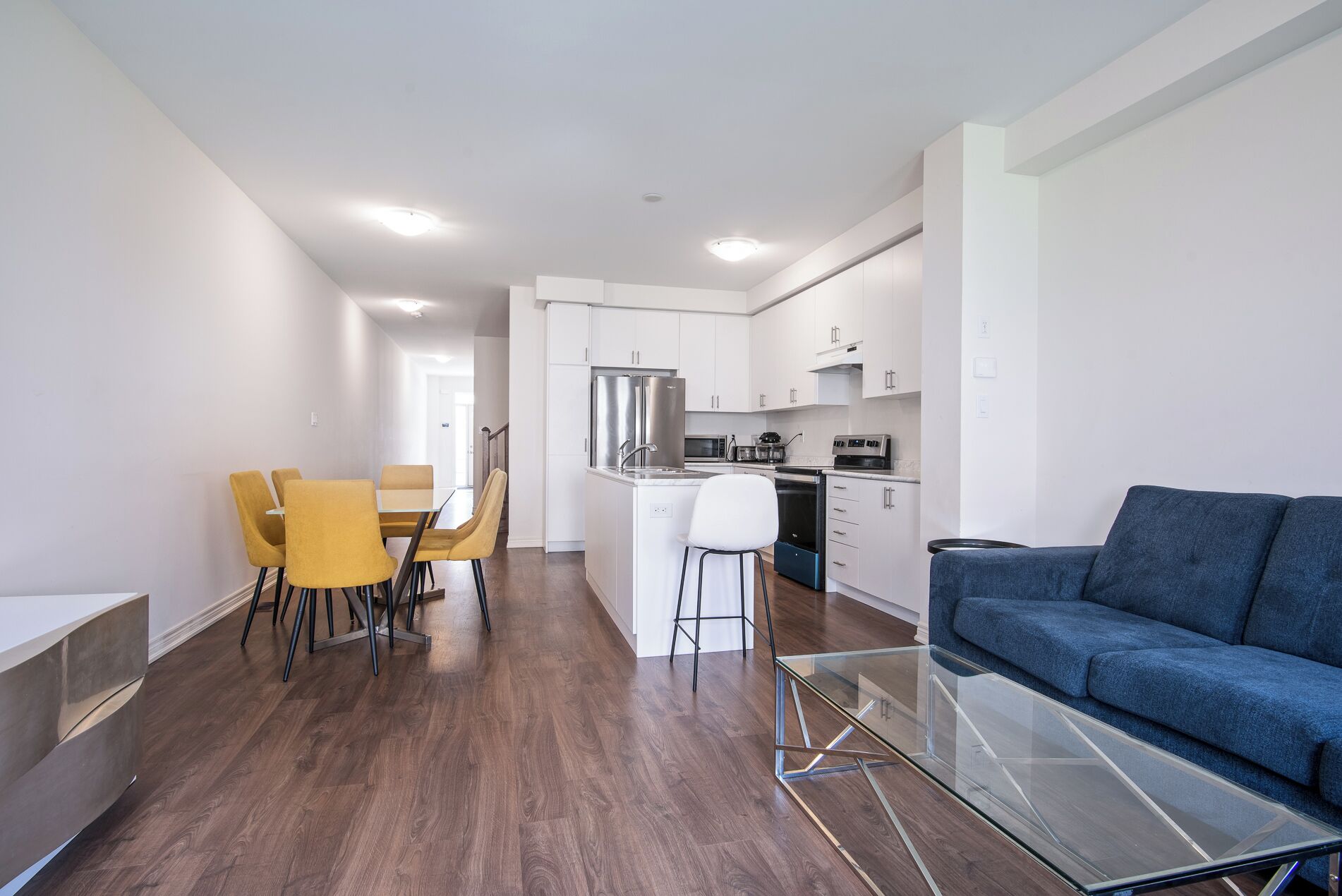 A modern kitchen with white cabinets, a stainless steel refrigerator, and a built-in oven.