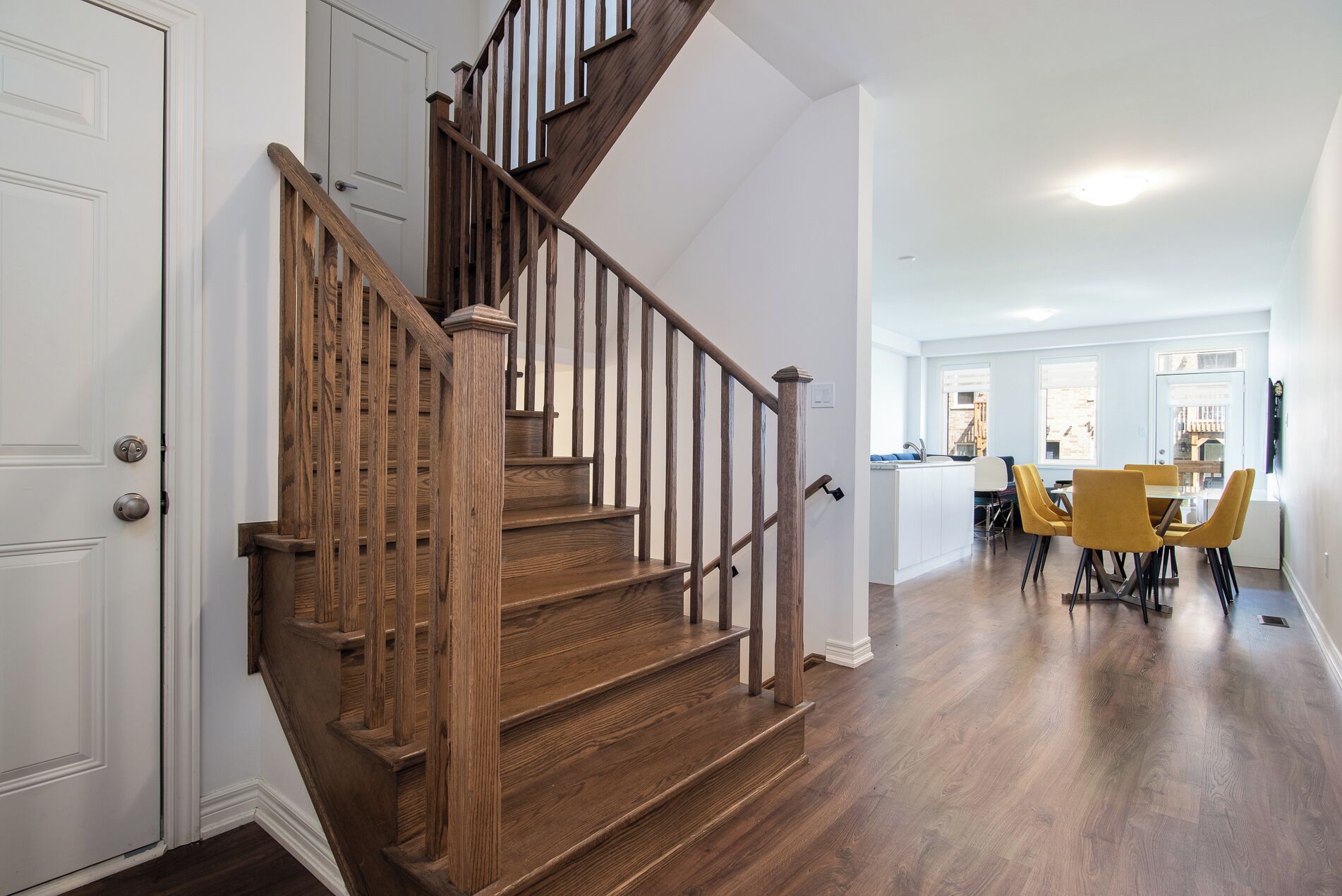 A wooden staircase leading to a dining area with yellow chairs.