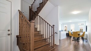 Una escalera de madera que conduce a un comedor con sillas amarillas.