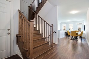 Eine Holztreppe führt zu einem Essbereich mit gelben Stühlen.