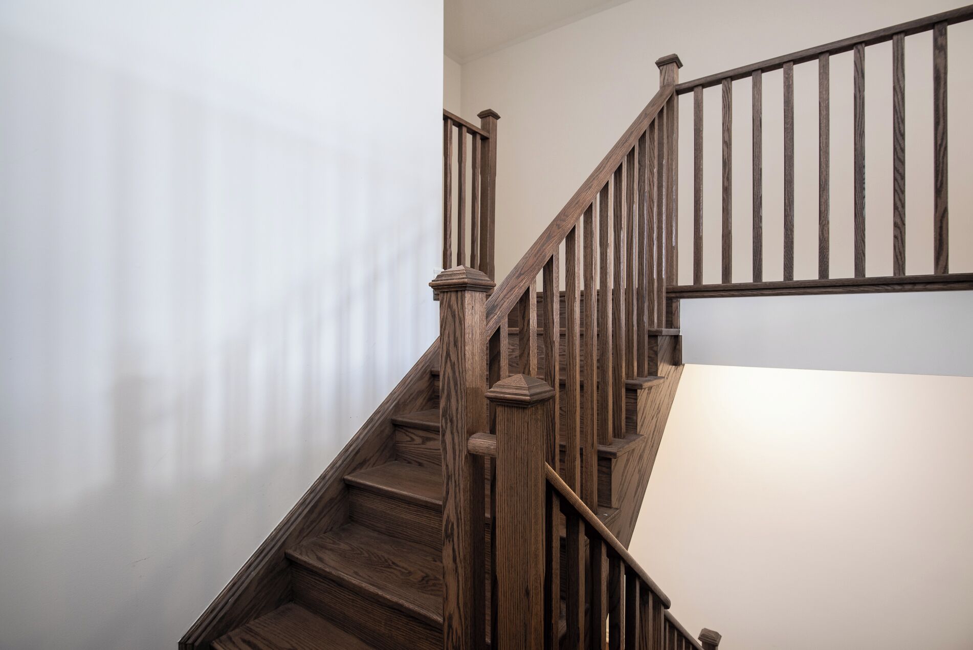 Una escalera de madera con barandilla y un rellano.