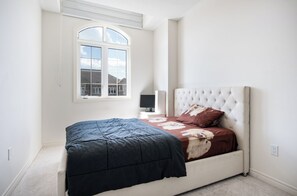 Ein Schlafzimmer mit Bett, Fenster, Nachttisch und Stuhl.