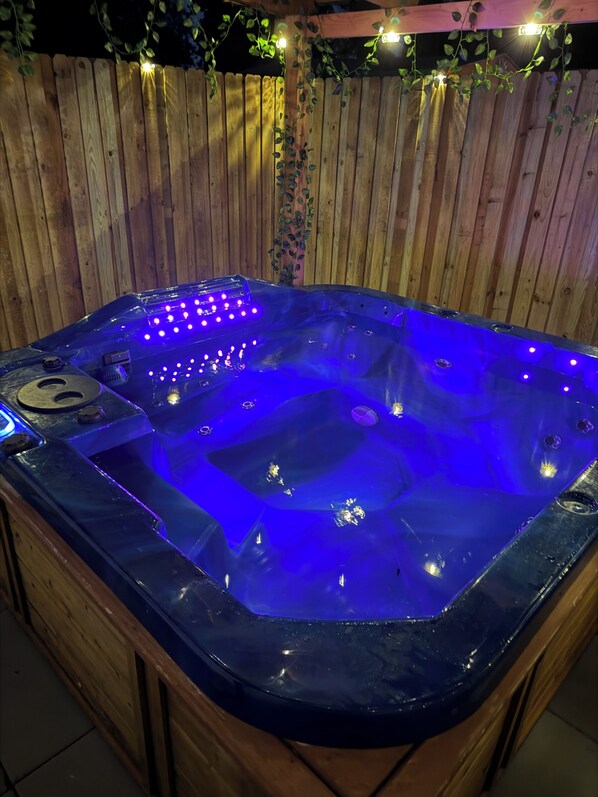A hot tub with blue LED lights, surrounded by a wooden fence and string lights. - A cozy retreat with a hot tub, just minutes from the beach and downtown (St. Petersburg)